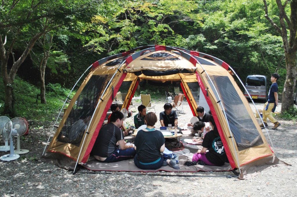 写真：木々に囲まれたテントの中でミーティング