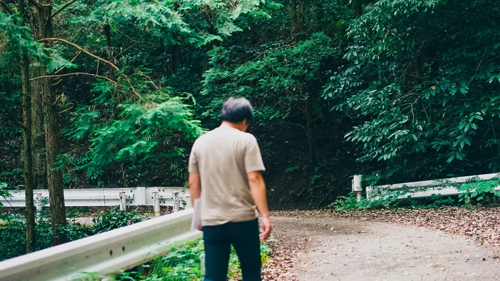 写真：山の中を歩く吉冨さんの後ろ姿